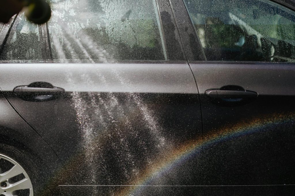 A gleaming freshly washed car reflecting sunlight in a professional car wash bay at Sparkle Motors